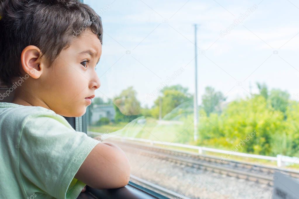 brunette boy looks sad from the train window
