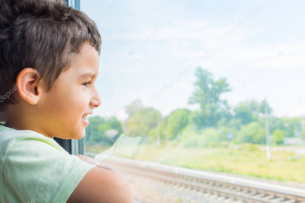 cheerful boy looks out the window of the train. Travel by rail