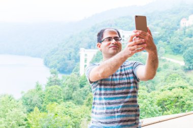 adam bir selfie bir dağ gölü arka plan üzerinde yapar.