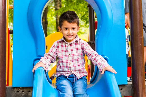 Junge Reitet Auf Rutsche Auf Spielplatz — Stockfoto