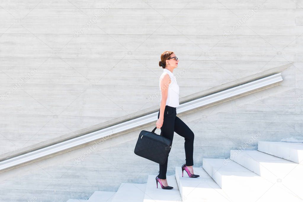 business woman with a laptop in her hands up the stairs