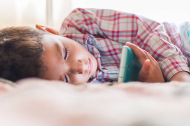 Çocuk telefon görünümlü yalan söylüyor. Becerikli olan bağımlılığını kavramı