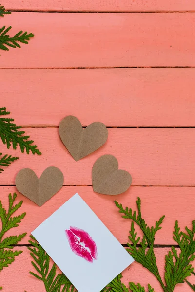 hearts and card with lip print on pink wooden background