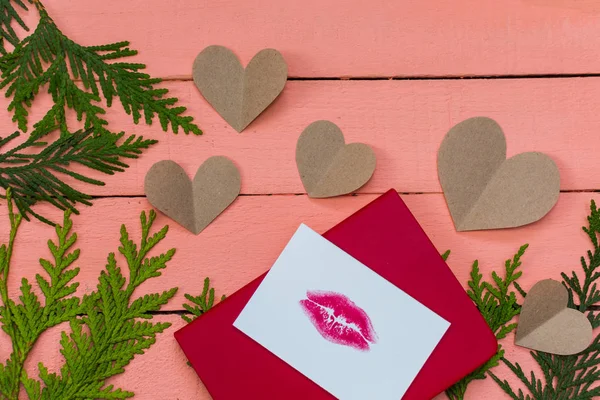 hearts and card with lip print on pink wooden background