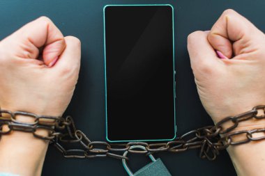elleri kolları bağlı olan bir zincir, smartphone. Engellilik, yasağı kavramı.