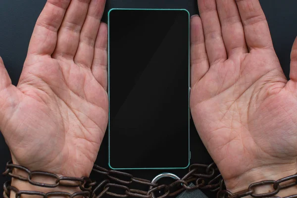 Hands tied with a chain, smartphone. the concept of disability, — Stock Photo, Image