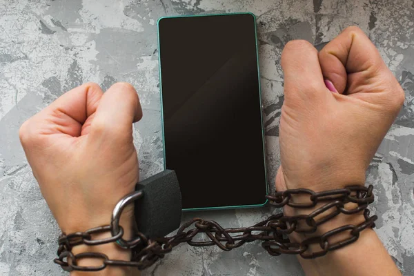 Hands tied with a chain, smartphone. the concept of disability, — Stock Photo, Image