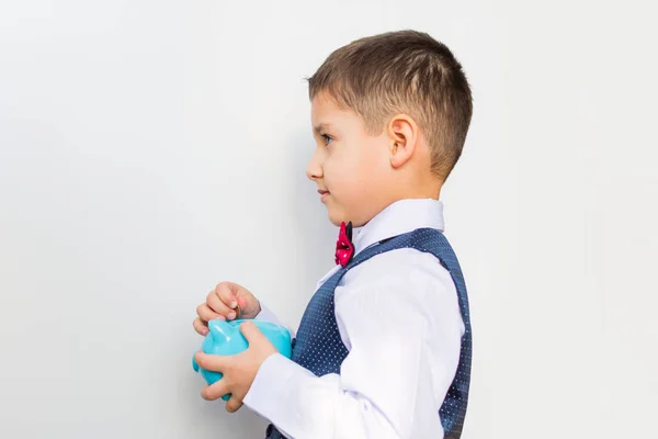 Niño con una alcancía en sus manos sobre un fondo blanco —  Fotos de Stock