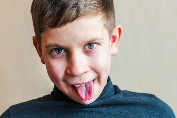 Adolescente chico muestra lengua en interior —  Fotos de Stock