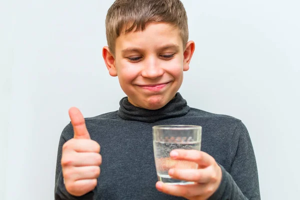 Adolescente chico sostiene un vaso de agua y muestra OK gesto —  Fotos de Stock