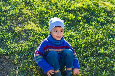 neşeli çocuk bir şapka ve çim üzerinde oturan kazak