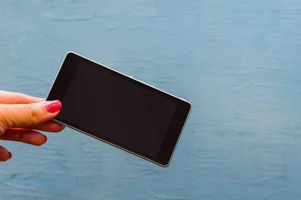 Smartphone in female hand on blue background — Stock Photo, Image