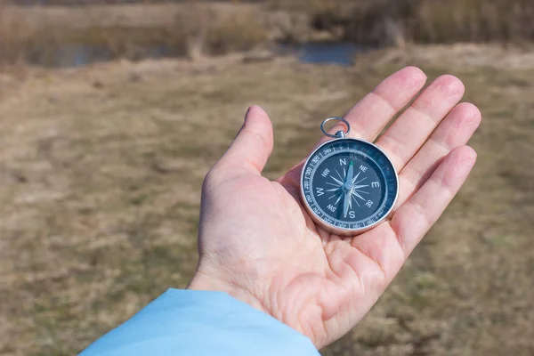 Kompass i en kvinnlig hand på en bakgrund av naturen — Stockfoto