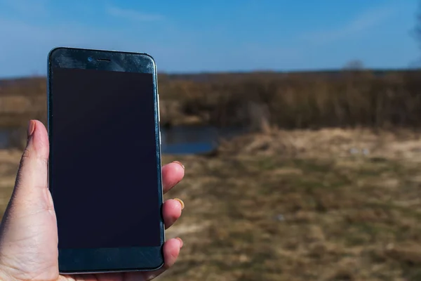 Smartphone in a woman's hand on the background of nature. copy s — Stock Photo, Image