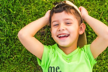 yaz aylarında çimenler üzerinde yatan neşeli gülümseyen çocuk