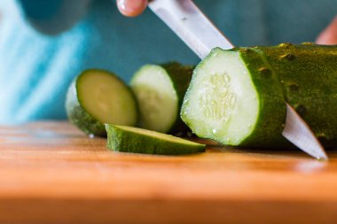 Kadın taze salatalık kesiyor.