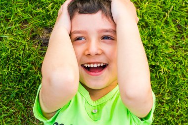 yaz aylarında çimenler üzerinde yatan neşeli gülümseyen çocuk