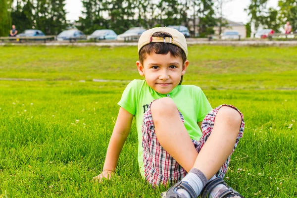 Niño feliz sentado en la hierba en el verano —  Fotos de Stock