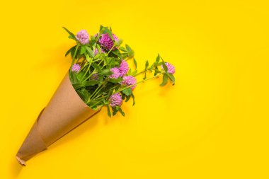 sarı bir arka plan üzerinde bir kağıt koni yonca buketi