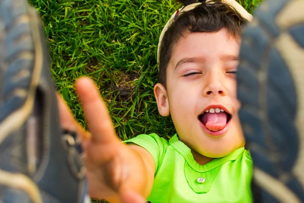 Alegre niño acostado en la hierba y levantó las piernas —  Fotos de Stock