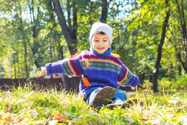 Chico en suéter y sombrero sentado en la hierba — Foto de Stock