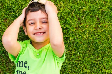 yaz aylarında çimenler üzerinde yatan neşeli gülümseyen çocuk
