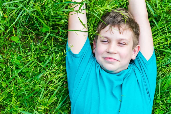 Счастливый мальчик-подросток лежит в траве летом — стоковое фото