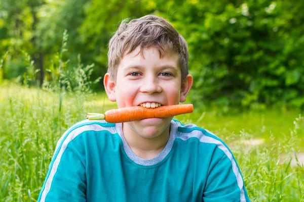 Adolescente chico en la naturaleza con la zanahoria —  Fotos de Stock