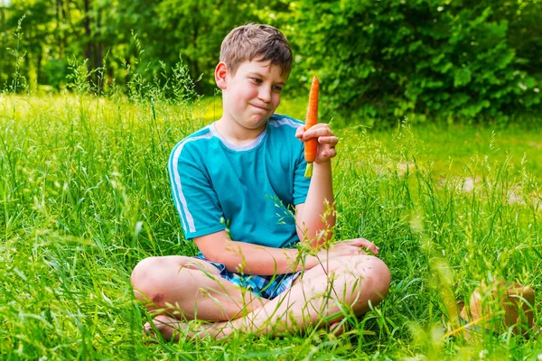 Adolescente chico en la naturaleza con la zanahoria — Foto de Stock
