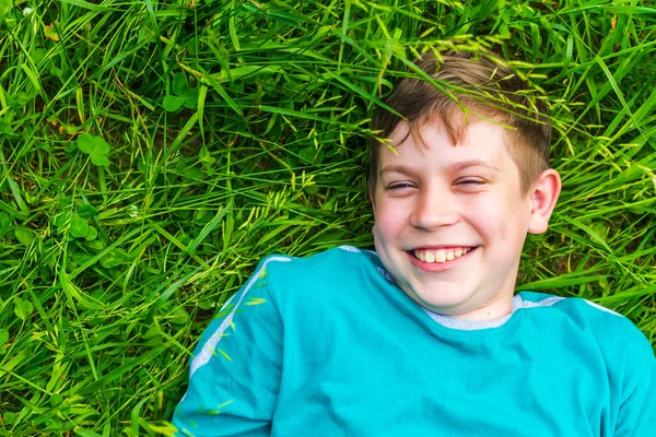 Счастливый мальчик-подросток лежит в траве летом — стоковое фото