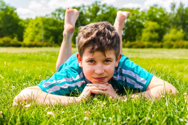 Мальчик-подросток, лежащий на траве на животе — стоковое фото
