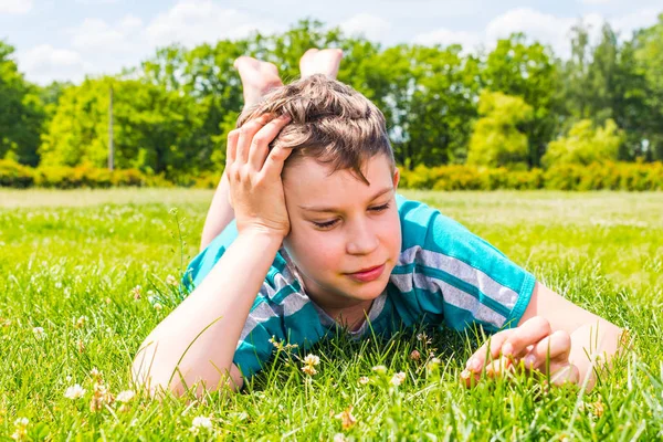 Adolescente chico acostado en su estómago en la hierba — Foto de Stock