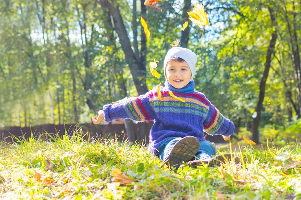 Мальчик в свитере и шляпе сидит на траве — стоковое фото