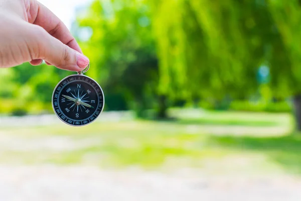 Kompass i en kvinnlig hand på en bakgrund av naturen — Stockfoto