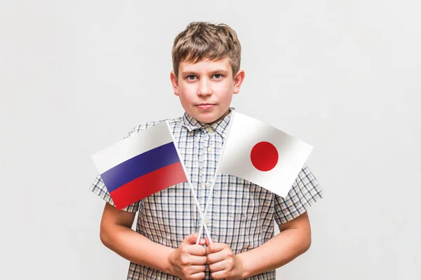 Teen boy holds the flags of the Russia and Japan — Stock Photo, Image