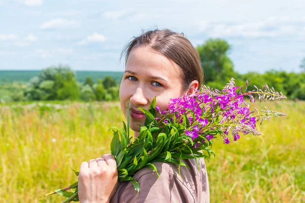 Mladá žena s buketou Chamaenerion angustifolium na — Stock fotografie