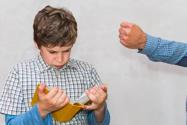 Papá le muestra su puño a su hijo. te hace leer un libro . — Foto de Stock