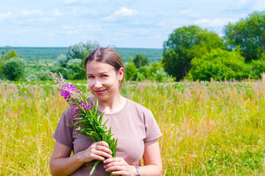 üzerinde Chamaenerion angustifolium bir buket ile genç kadın 