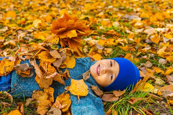 Veselý chlapec ležící v listoví. podzimní podzim — Stock fotografie