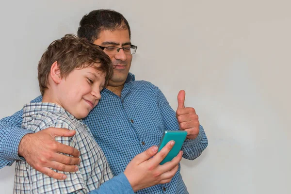 Папа и сын смотрят на телефон вместе и улыбаются. — стоковое фото