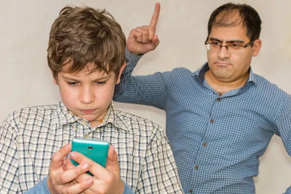 Föräldern grälar sonen. beroende på smartphone. — Stockfoto