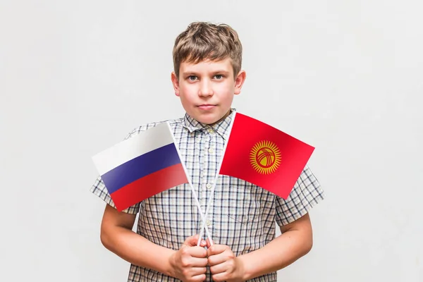 Tiener jongen houdt de vlaggen van de Rusland en Kirgizië — Stockfoto