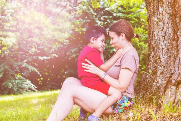 Mamá y su hijo se divierten bajo un árbol en el verano. tonificado — Foto de Stock
