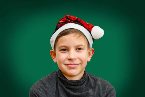 Мальчик-подросток в шляпе Санта на зеленом фоне — стоковое фото