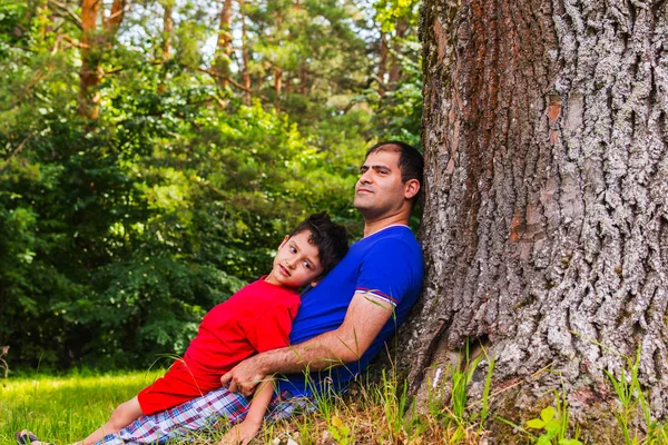 Padre e hijo descansando bajo un árbol en el verano —  Fotos de Stock