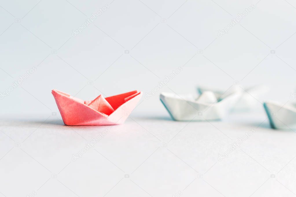 several blue and one red paper boat. The concept of leader, succ