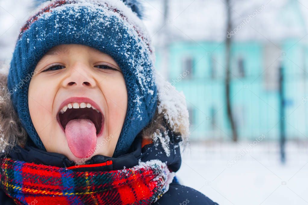 boy stuck out his tongue and catches snowflakes