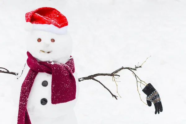 Lustiger Schneemann in Santa-Schal und Mütze auf schneebedecktem Hintergrund — Stockfoto