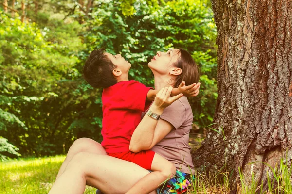 A mãe e o filho divertem-se debaixo de uma árvore no verão. tonificado — Fotografia de Stock