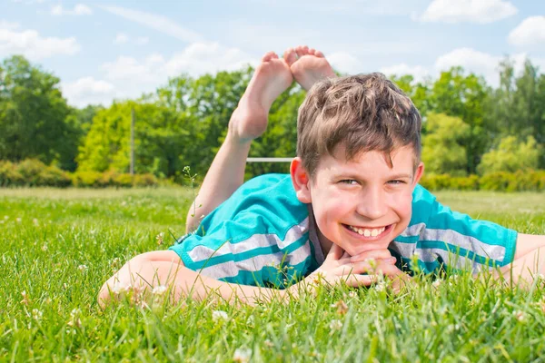 Sorridente Ragazzo Sdraiato Sull Erba Sul Suo Stomaco Foto Stock